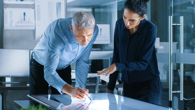 A man and a woman working at a drawing table.