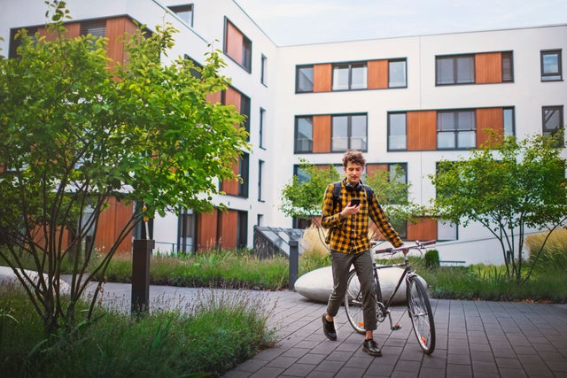 young man with bicycle walking outside a residential building