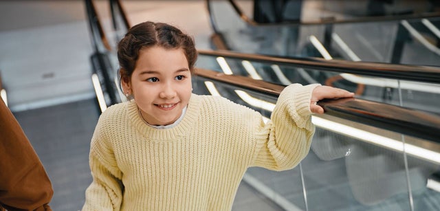 Child holding escalator handrail