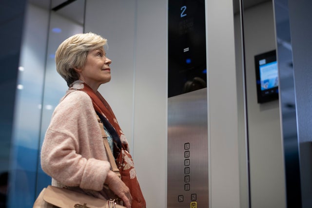 Lady in an elevator looking at the door.
