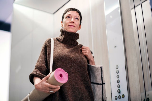 Woman in an elevator carrying a yoga mat