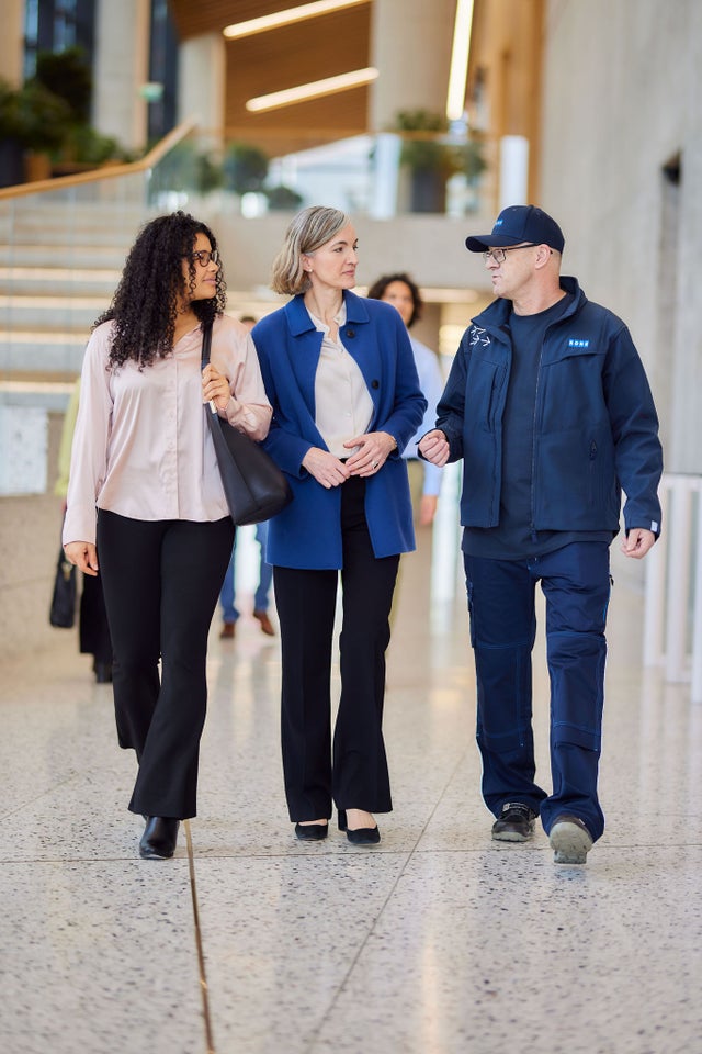 KONE technician walking with two women in a lobby