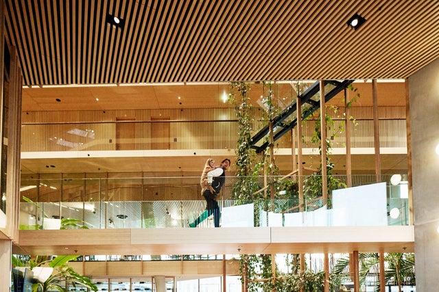 Man walking inside a building on a bridge with a girl on his backpack. 