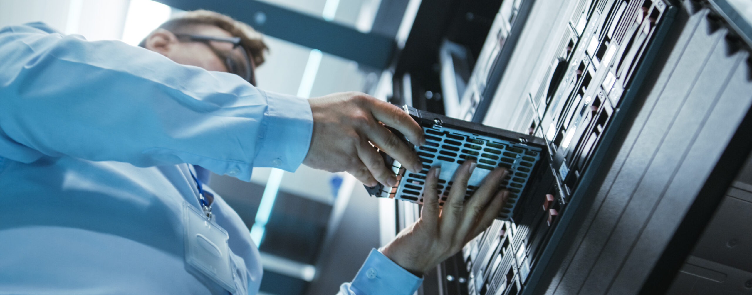 Long Angle Shot In Fully Working Data Center of IT Engineer Installing Hard Drive into Server Rack. Detailed and Technically Accurate Footage.